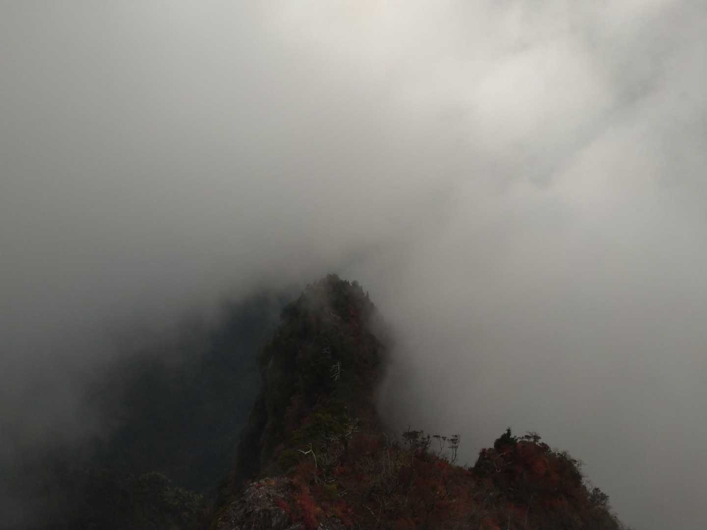 雲の切れ間から見えた岩峰と手前の紅葉